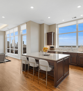 A large kitchen with a large island with white chairs